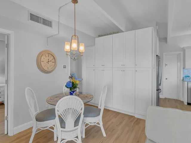 a dining room with a table chairs a clock and a view of kitchen