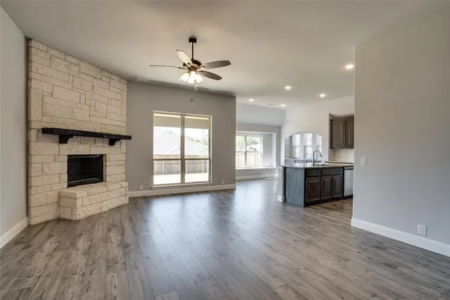 a view of an empty room with a kitchen and a fireplace