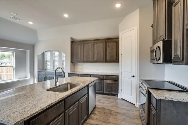 a kitchen with a sink dishwasher a stove and a refrigerator with wooden floor