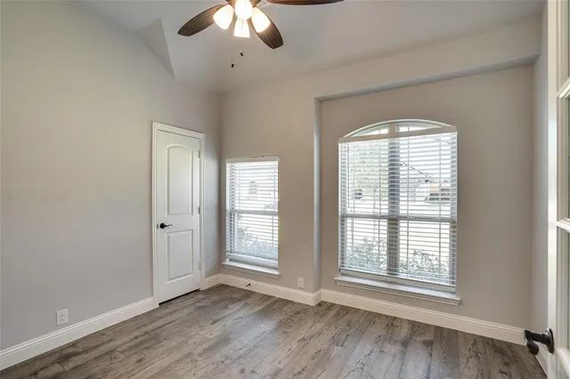 a view of an empty room with a window and wooden floor