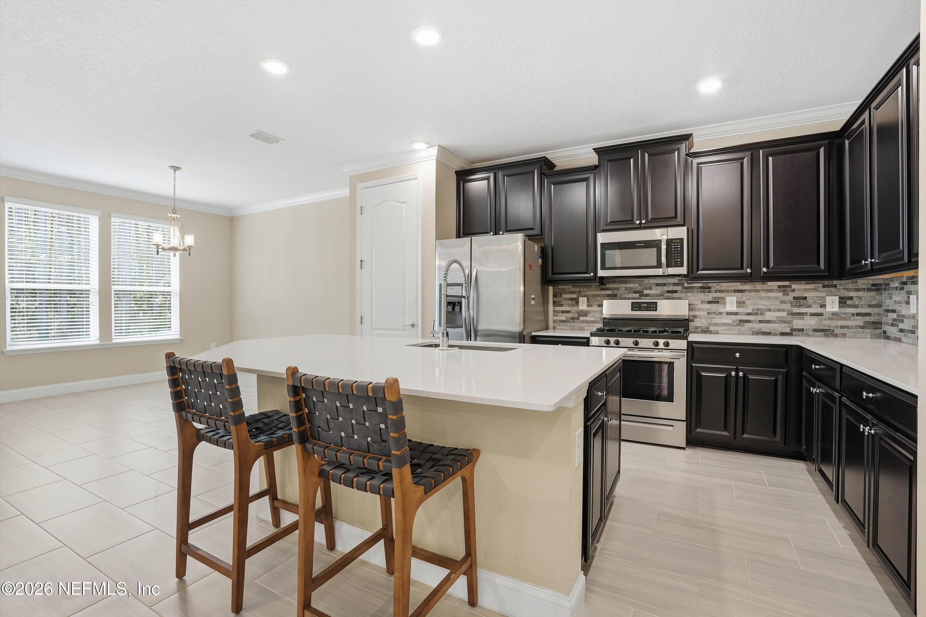 309 Coco Point St. Augustine, FL 32092 - Photo 14 of 50 a kitchen with stainless steel appliances kitchen island granite countertop a stove a refrigerator a sink a dining table and chairs