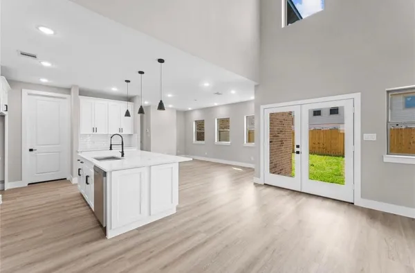 a kitchen with stainless steel appliances granite countertop a stove a sink a refrigerator and white cabinets with wooden floor