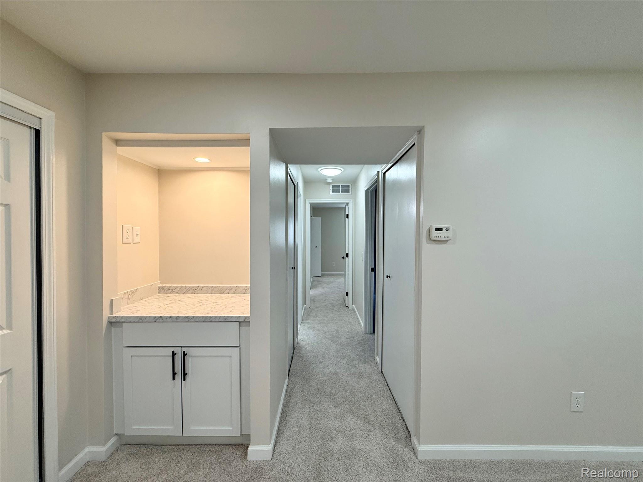 29870 West 12 Mile Road, Unit 703 Farmington, MI 48334 - Photo 14 of 40 Built-in dry bar featuring a light-toned countertop, white cabinetry with dark hardware, recessed lighting, and wall outlets