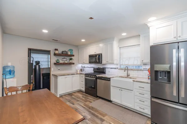 a kitchen that has a lot of cabinets a sink and appliances in it