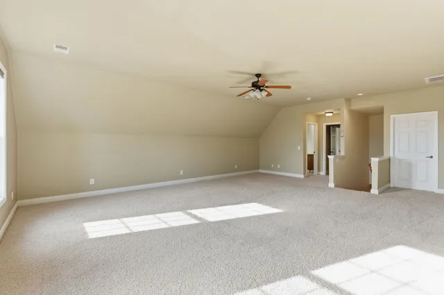 a view of an empty room with window and chandelier fan