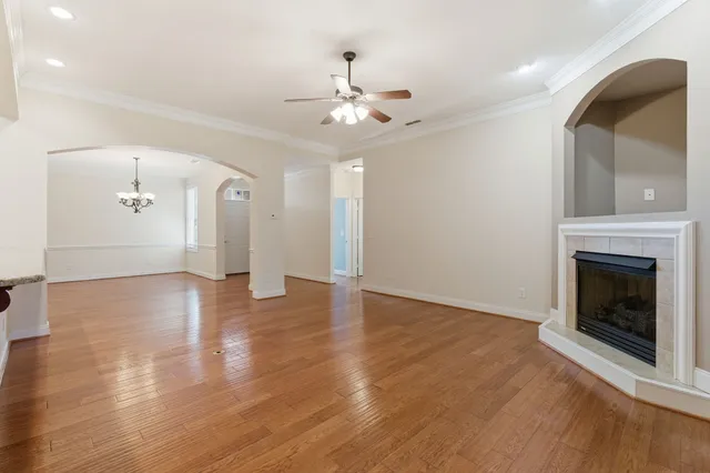 a view of an empty room with wooden floor fireplace and a window
