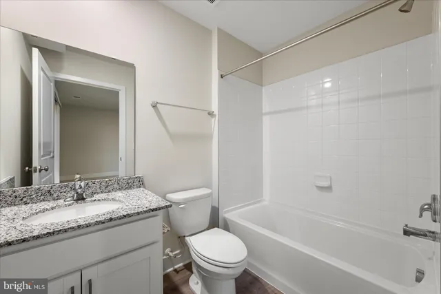 a bathroom with a granite countertop sink a toilet and a bathtub