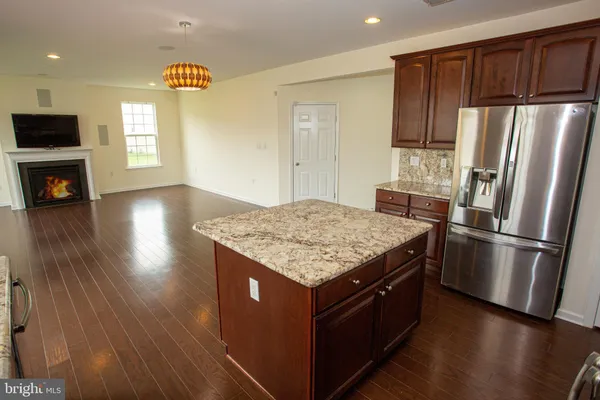 a kitchen with kitchen island granite countertop stainless steel appliances a stove top oven a sink and a refrigerator