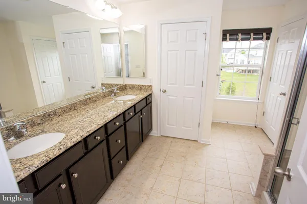 a bathroom with a granite countertop sink a mirror and a bathtub