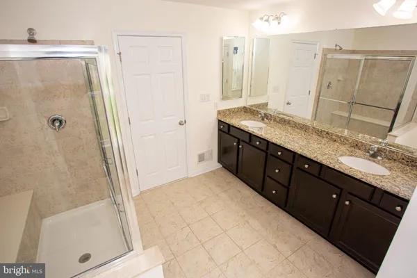 a bathroom with a granite countertop sink a mirror and a shower
