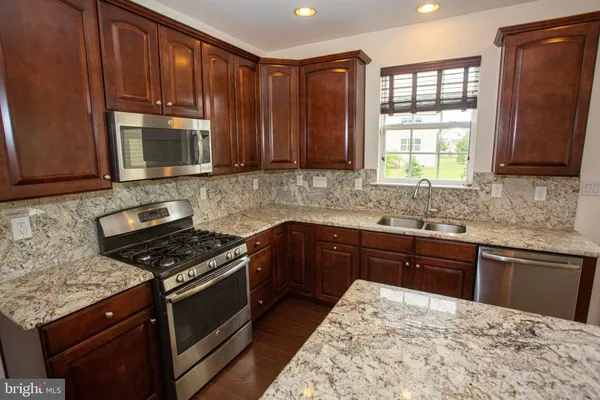 a kitchen with stainless steel appliances granite countertop wooden cabinets a stove top oven with a sink and dishwasher