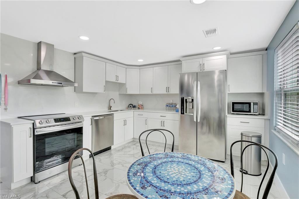 1009 Ridge Street Naples, FL 34103 - Photo 6 of 30 Kitchen featuring stainless steel appliances, light marble finish flooring, white cabinetry, and recessed lighting
