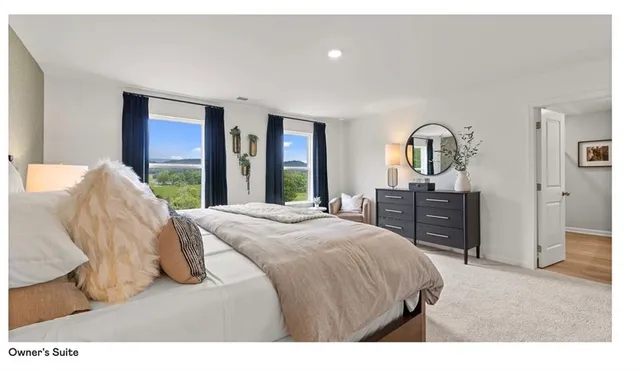 a spacious bedroom with a bed a dresser and large mirror