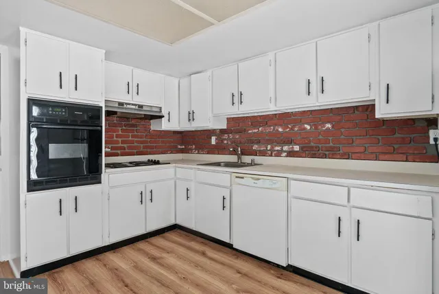 a kitchen with white cabinets and sink