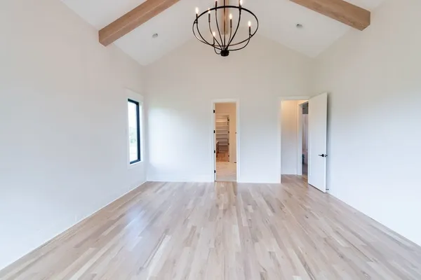 a view of empty room with wooden floor and a kitchen