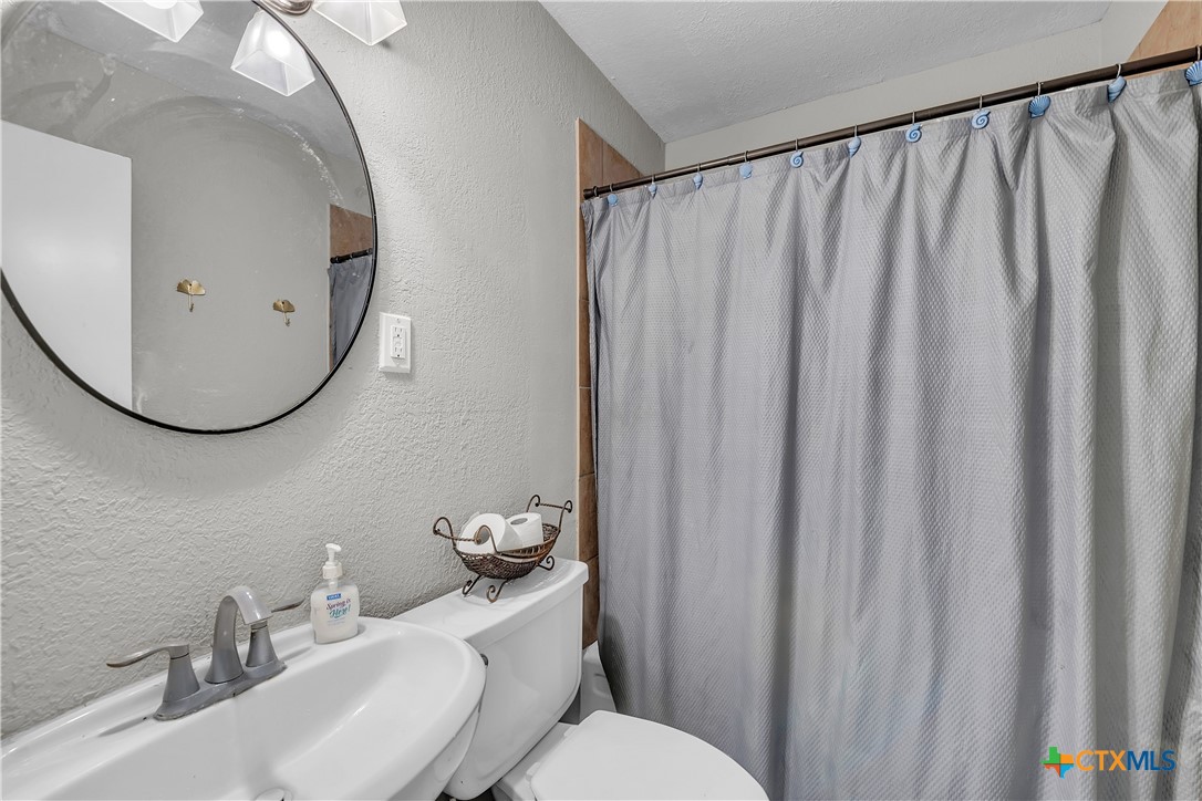 1001 West 8th Street Cameron, TX 76520 - Photo 12 of 20 a bathroom with a sink mirror and toilet