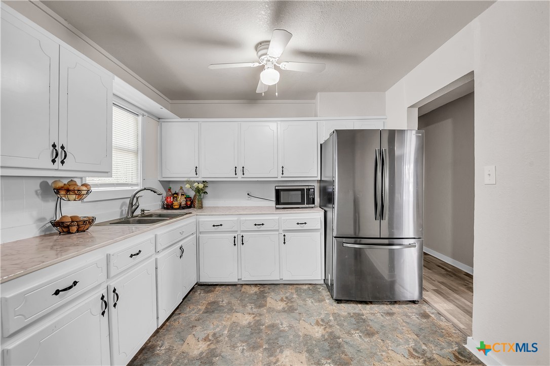 1001 West 8th Street Cameron, TX 76520 - Photo 8 of 20 a kitchen with stainless steel appliances a refrigerator sink and cabinets
