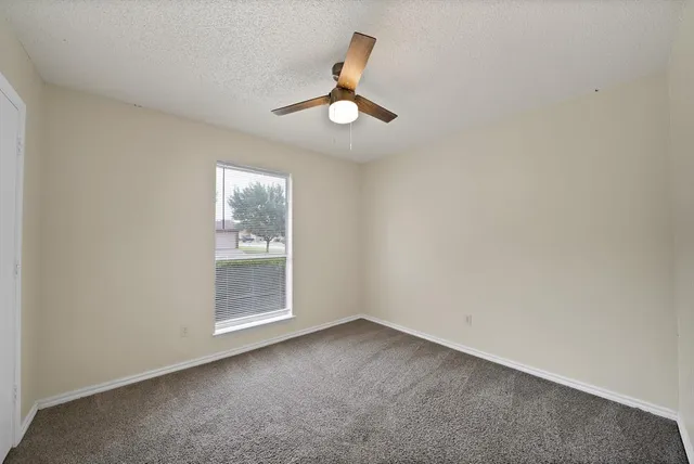 an empty room with a window and ceiling fan