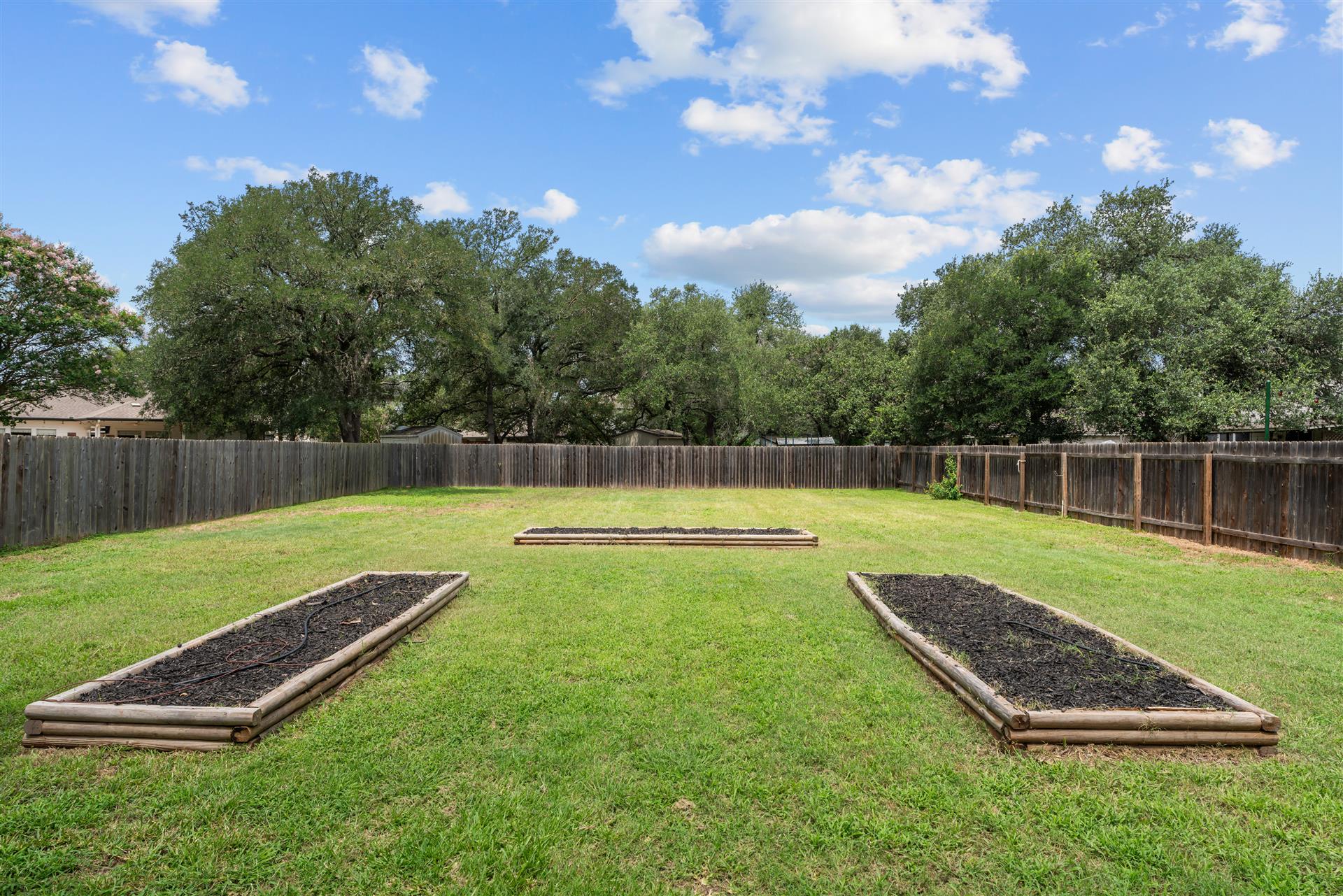 4725 Tello Path Austin, TX 78749 - Photo 3 of 34 A spacious backyard features three raised garden beds, perfect for cultivating a vibrant landscape.