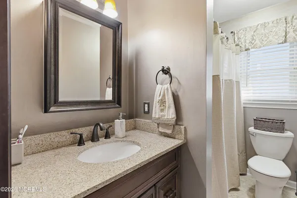 a bathroom with a granite countertop sink toilet and a mirror