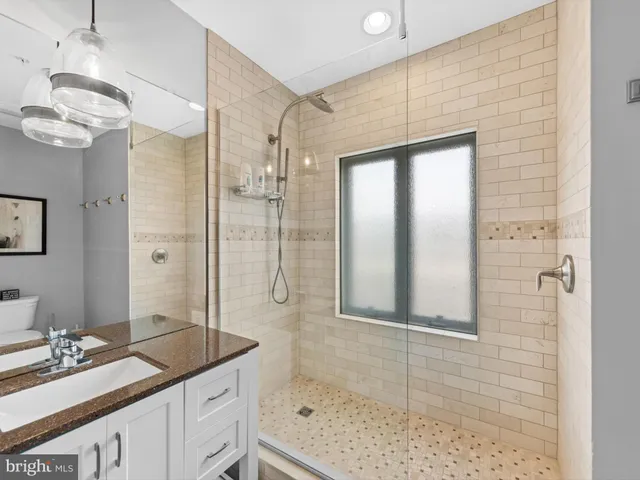 a bathroom with a granite countertop sink a mirror and shower