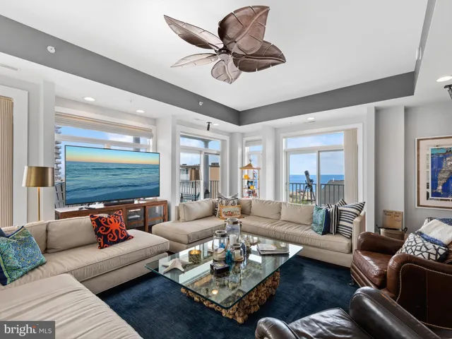 a living room with furniture ceiling fan and a large window