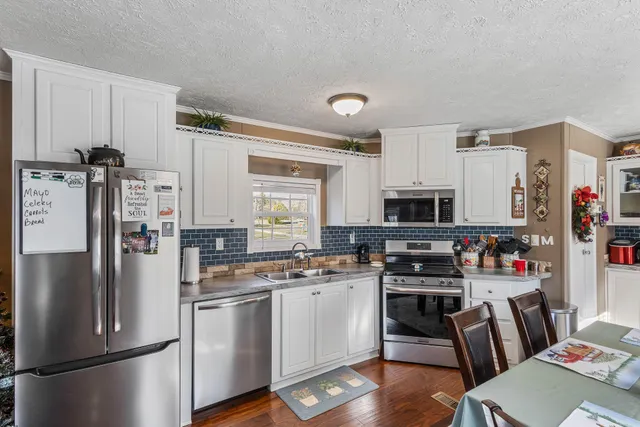 a kitchen with stainless steel appliances granite countertop a stove top oven a sink dishwasher a dining table and chairs with wooden floor