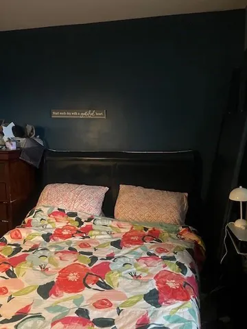 a bedroom with a bed and a lamp on dresser