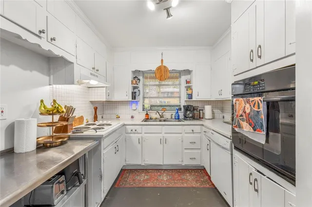 a kitchen with stainless steel appliances granite countertop a stove a sink and white cabinets
