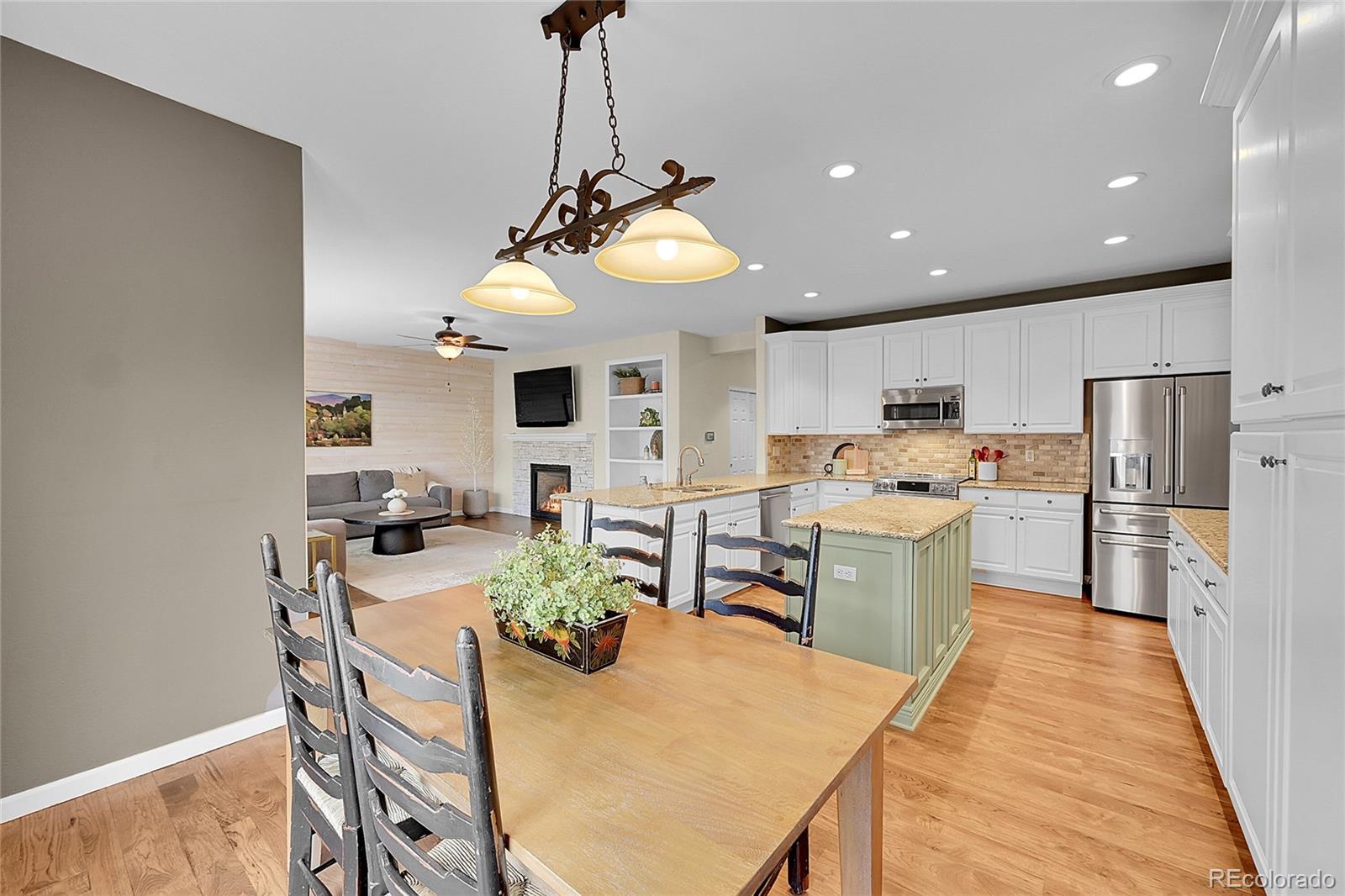 9424 South Hackberry Lane Highlands Ranch, CO 80129 - Photo 15 of 47 a kitchen with stainless steel appliances kitchen island granite countertop a dining table chairs refrigerator and sink