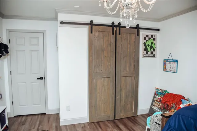 a view of a bedroom with wooden floor closet and windows