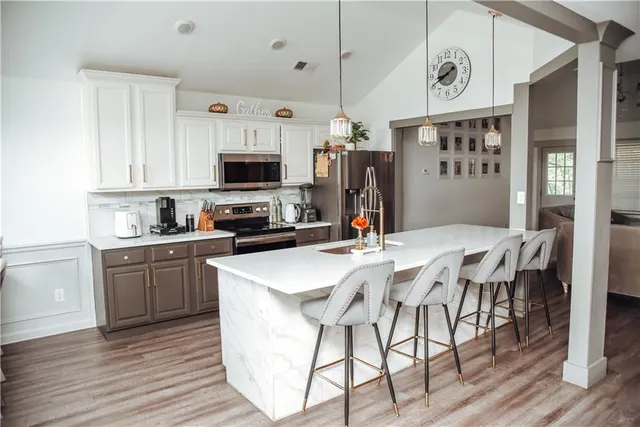 a kitchen with stainless steel appliances granite countertop a stove a sink dishwasher a refrigerator a microwave oven with cabinets and wooden floor