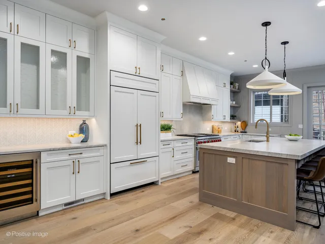 a kitchen with stainless steel appliances granite countertop a sink a stove a refrigerator and island with wooden floor