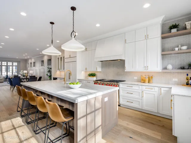 a kitchen with stainless steel appliances a stove a sink a refrigerator a center island and white cabinets