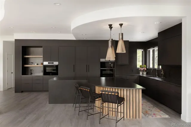 a kitchen with granite countertop a stove a refrigerator a sink a dining table and chairs with wooden floor