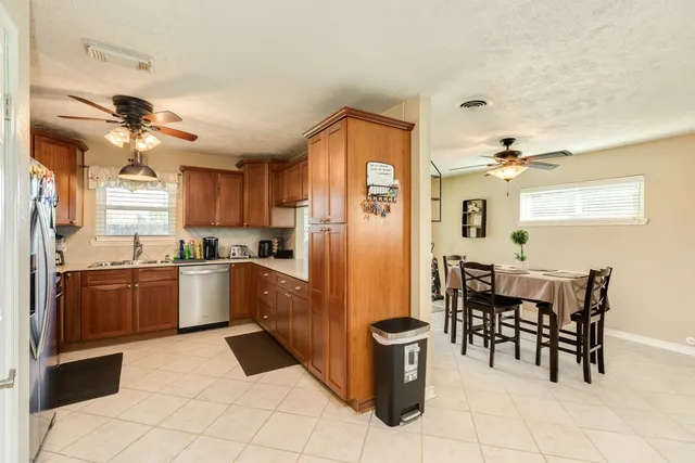 a kitchen with stainless steel appliances granite countertop a refrigerator a sink dishwasher a dining table and chairs with wooden floor