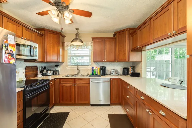 a kitchen with stainless steel appliances granite countertop a sink a stove cabinets counter space and a window