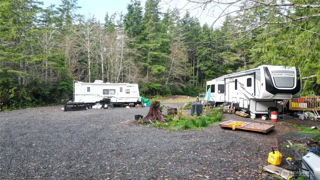 a front view of a house with lots of trees and plants