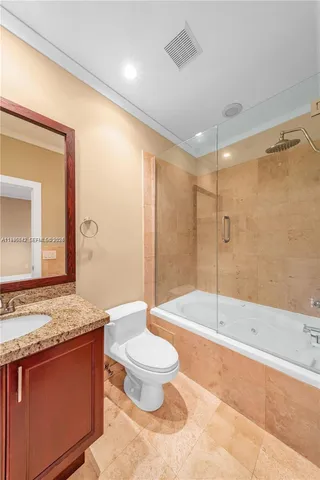 a spacious bathroom with a granite countertop sink a toilet a mirror and bathtub