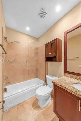 a bathroom with a granite countertop toilet sink and mirror
