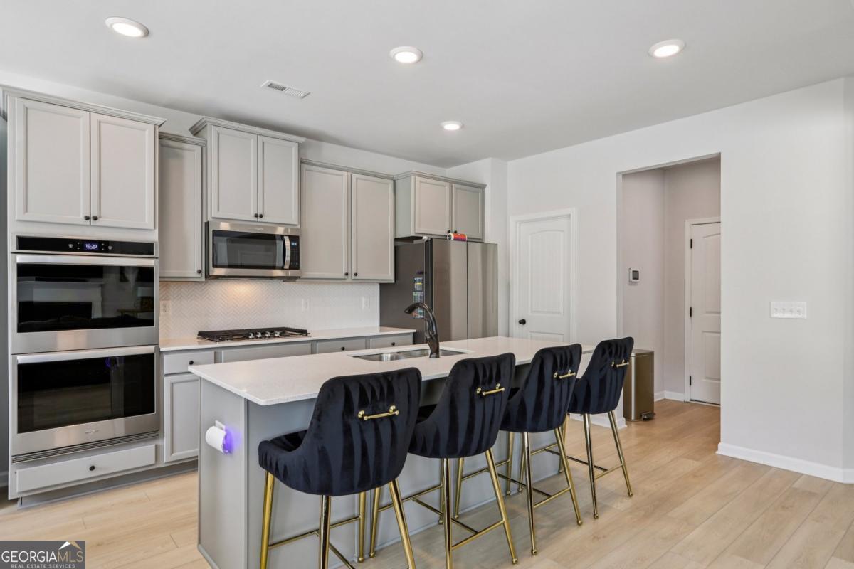 4774 Sultana Way Atlanta, GA 30331 - Photo 8 of 25 a kitchen with stainless steel appliances granite countertop a stove a sink a microwave a dining table and chairs with wooden floor