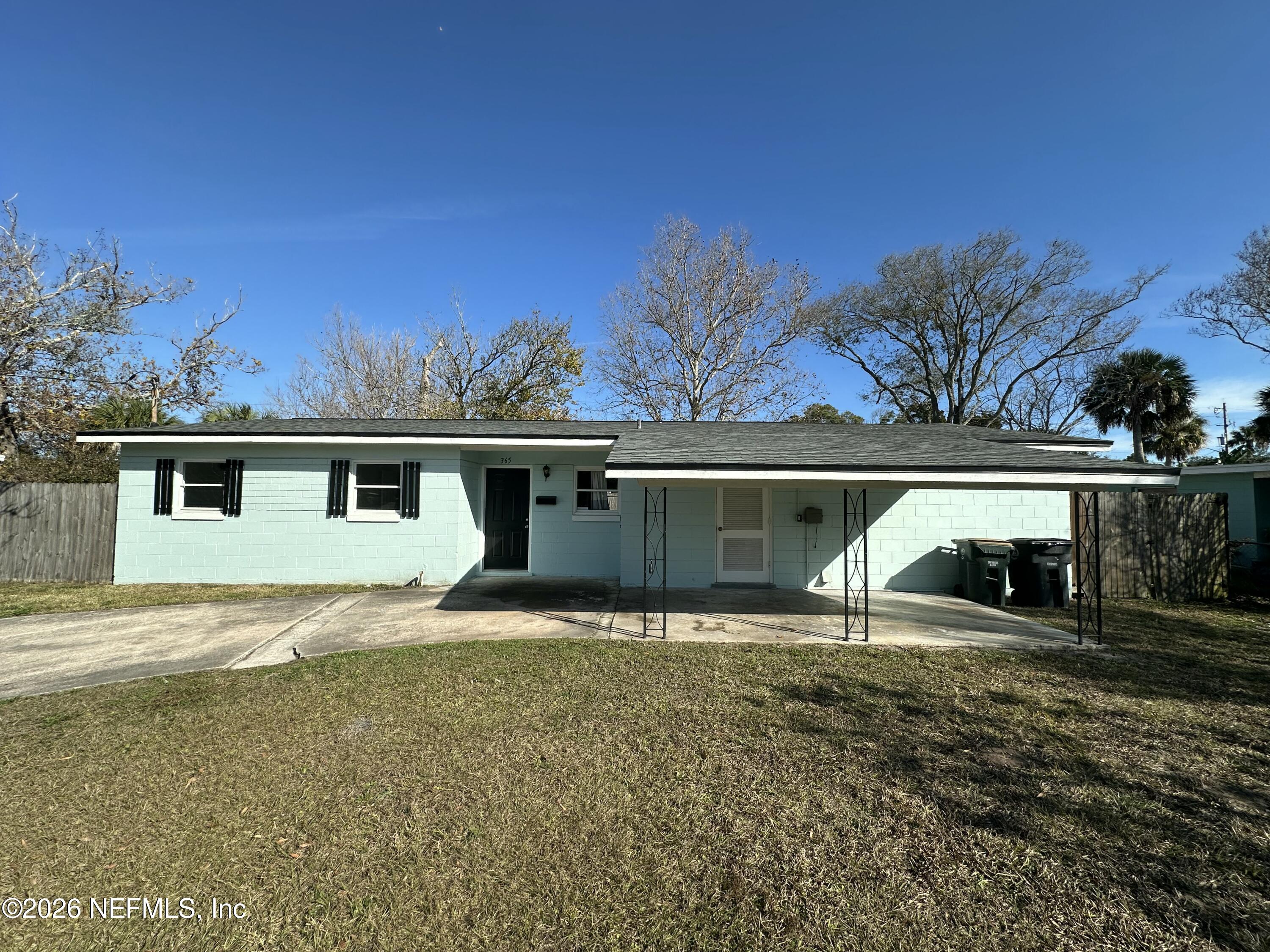 a view of house with backyard and trees in the background