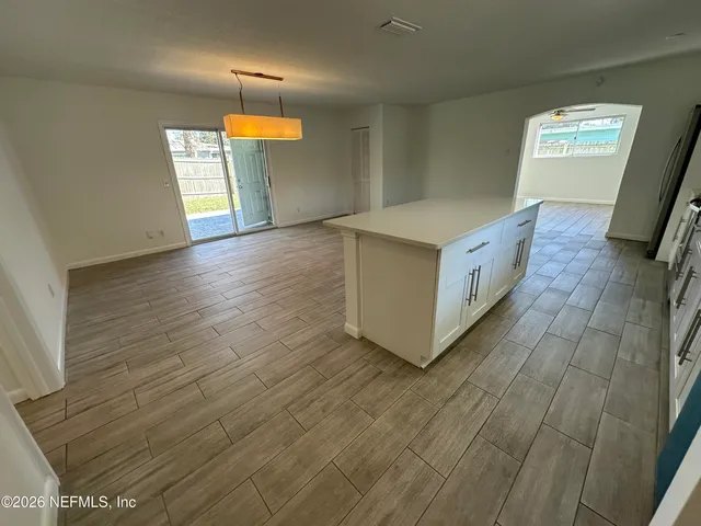 a view of an empty room with window and wooden floor