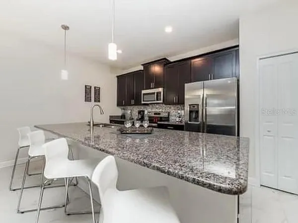 a kitchen with stainless steel appliances granite countertop a sink refrigerator and microwave