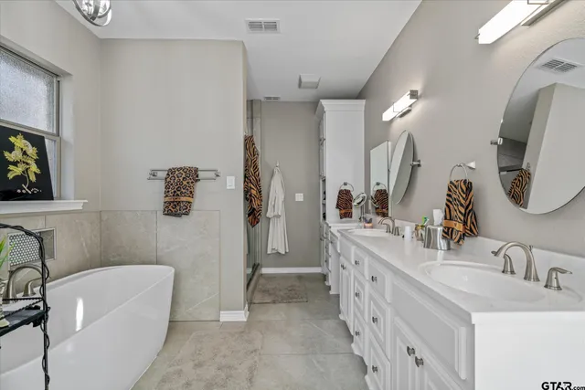 a bathroom with a double vanity sink a mirror a bathtub and shower