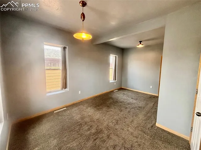 a view of an empty room and window and chandelier fan