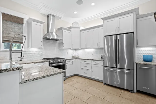 a kitchen with stainless steel appliances granite countertop a refrigerator a sink and white cabinets