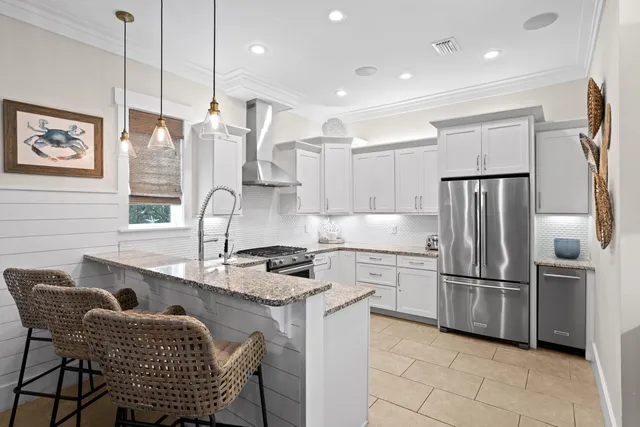 a kitchen with stainless steel appliances granite countertop a refrigerator a sink a stove a dining table and chairs