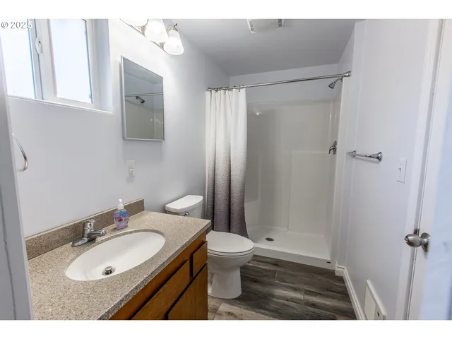 a bathroom with a granite countertop sink toilet a mirror a vanity and shower