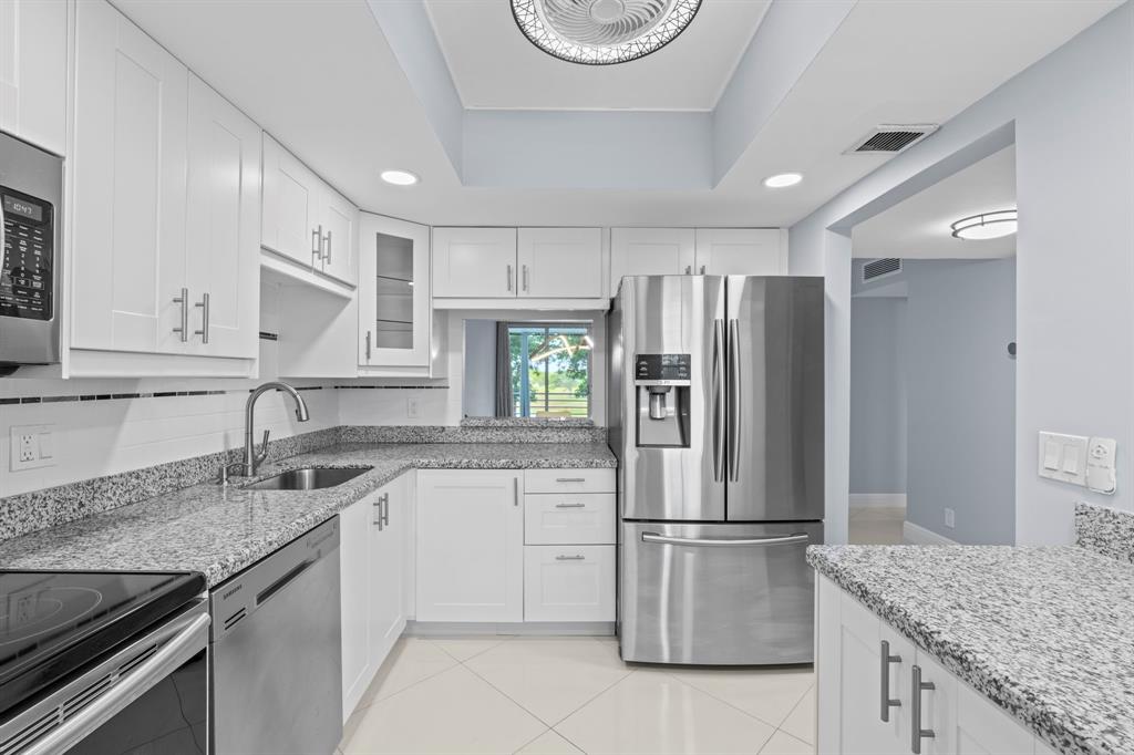 3090 North Course Drive, Unit 309 Pompano Beach, FL 33069 - Photo 2 of 21 a kitchen with stainless steel appliances granite countertop a sink stove and refrigerator